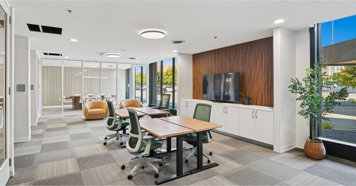 The coworking and business center at The Pulse OKC with desks, chairs, and a large wall-mounted TV.