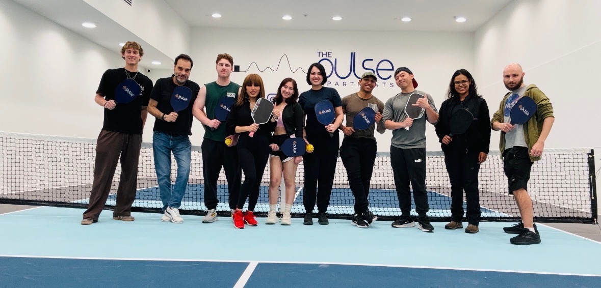 Residents at The Pulse OKC standing together on the indoor pickleball court.
